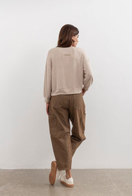 Person wearing a beige sweater and brown cargo pants against a white background