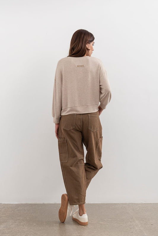 Person wearing a beige sweater and brown cargo pants against a white background