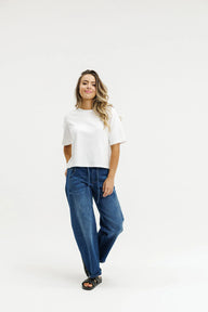 Woman wearing a white t-shirt and blue jeans on a white background
