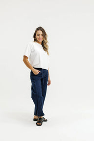 Woman wearing a white top and navy pants on a white background