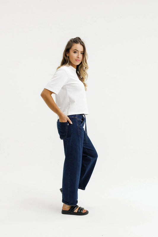 Woman wearing a white top and dark blue jeans on a white background