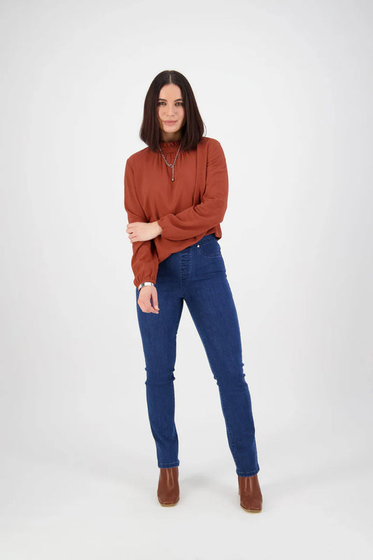 Woman wearing a rust-colored sweater and blue jeans on a white background