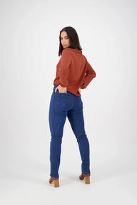 Woman wearing a rust-colored sweater and blue jeans on a white background
