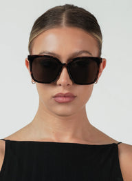 Woman wearing dark sunglasses against a plain background