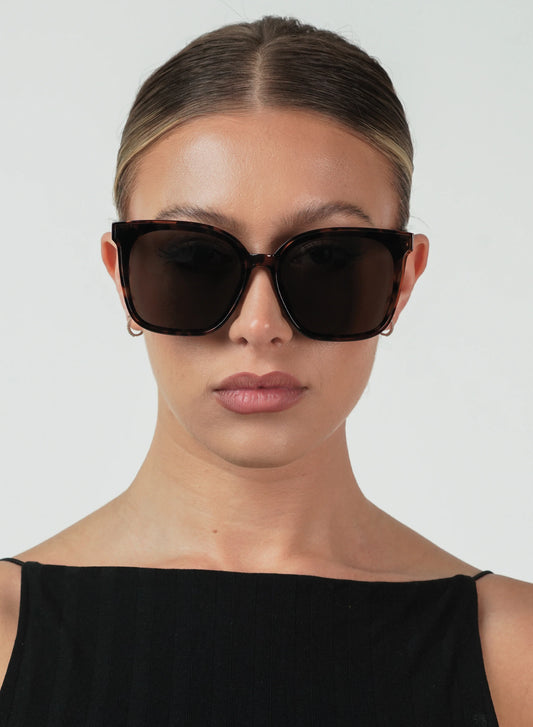Woman wearing dark sunglasses against a plain background