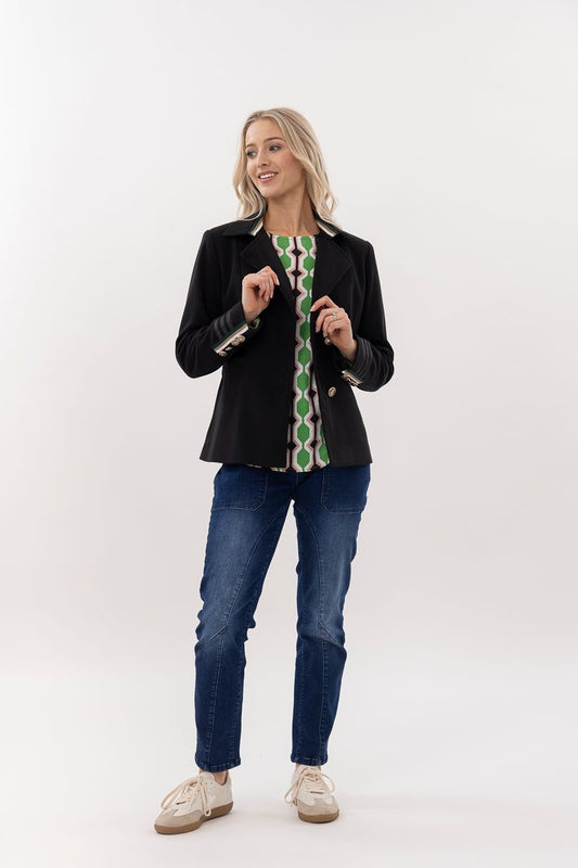 Woman wearing a black jacket with green patterned accents and blue jeans on a white background