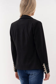 Black blazer with decorative buttons worn by a person on a white background