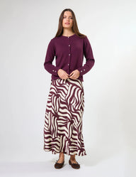 Woman wearing a long purple cardigan and zebra-patterned skirt on a white background