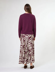 Woman wearing a purple sweater and zebra print pants on a white background