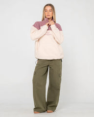 Person wearing a two-tone pullover with beige and purple and green cargo pants on a white background