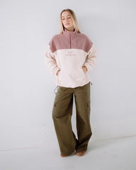 Person wearing a two-tone pullover with a logo and cargo pants on a white background