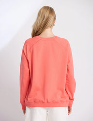 Person wearing a coral sweatshirt against a white background