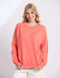 Woman wearing a coral sweatshirt on a white background