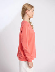 Woman wearing a coral sweatshirt on a white background