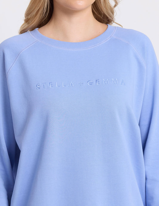 Light blue sweatshirt with 'Stella + Gemma' branding on a plain background