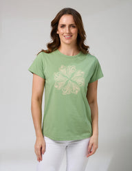 Woman wearing a green t-shirt with a floral design on a plain background