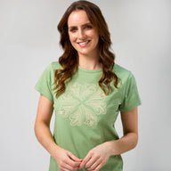Woman wearing a green t-shirt with a white floral design on a plain background