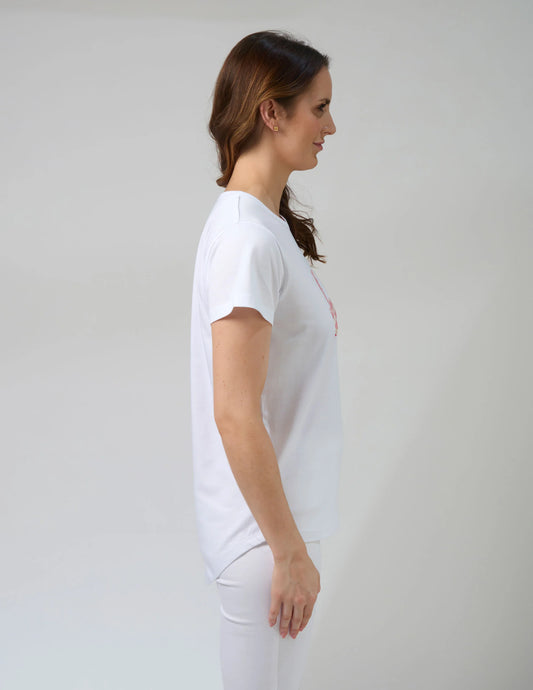 Woman wearing a white t-shirt and pants against a plain background