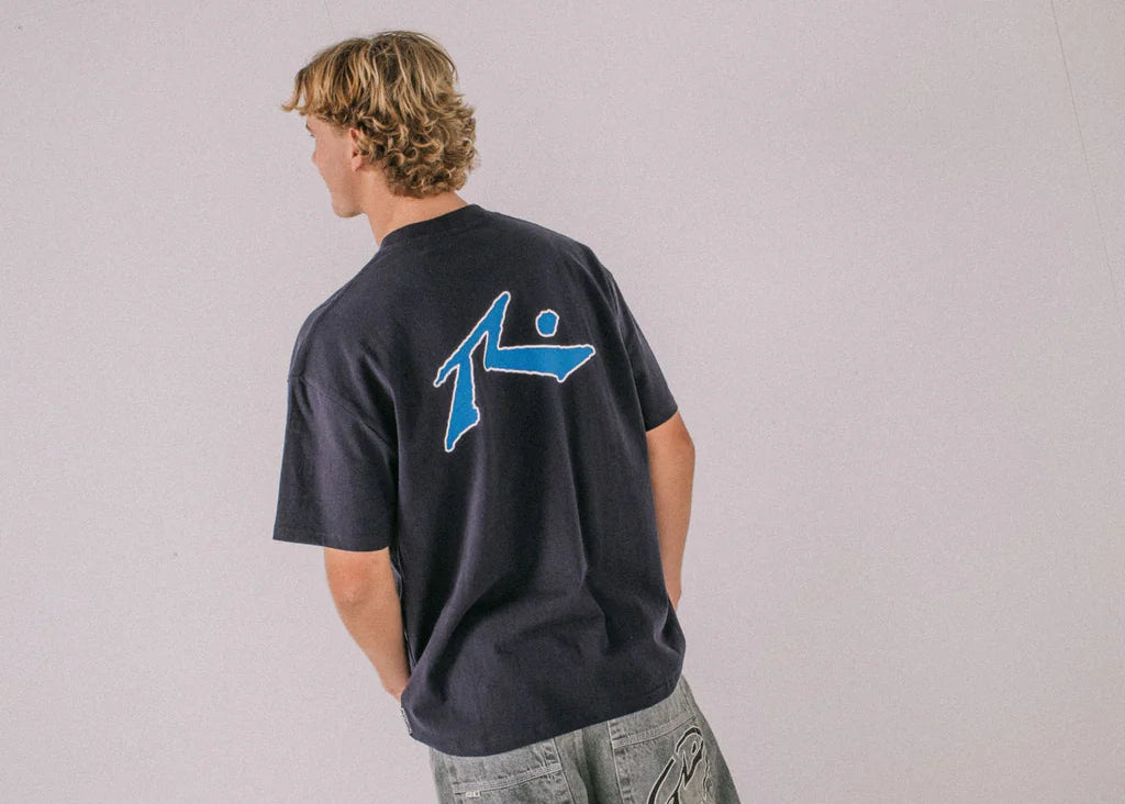 Person wearing a navy blue t-shirt with a logo on a light gray background