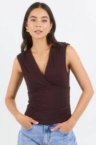 Woman wearing a brown sleeveless top with a plain background