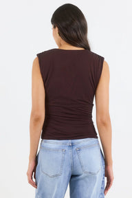 Woman wearing a brown sleeveless top and blue jeans on a white background