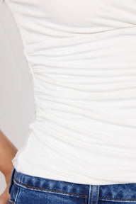 Close-up of a person wearing a white top and blue jeans.
