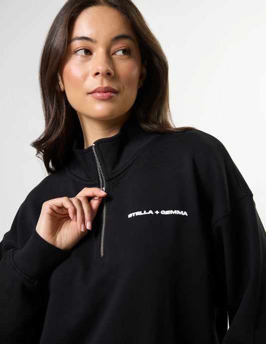 Woman wearing a black hoodie with 'Stella + Gemma' logo on a light gray background