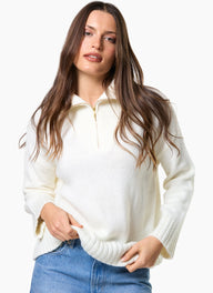 Woman wearing a white zip-up sweater and blue jeans on a white background
