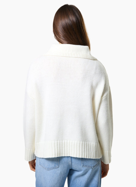 Person wearing a white sweater and light blue jeans on a white background