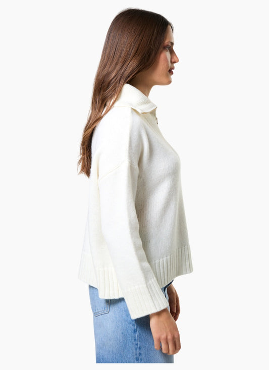 Woman wearing a white turtleneck sweater and blue jeans on a white background