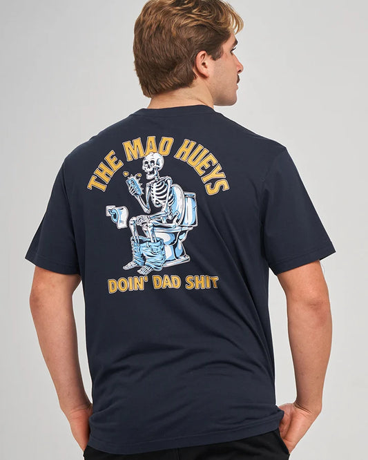 A man wearing a navy blue t-shirt, viewed from the back. The shirt features a large graphic print of a skeleton sitting on a toilet holding a beer mug, with yellow text reading 'THE MAD HEWEYS' above and 'DOIN' DAD SHIT' below.