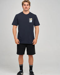 A man modeling a navy blue short-sleeve t-shirt with a small graphic on the left chest, paired with black athletic shorts, black socks, and black sneakers, against a light gray studio background.
