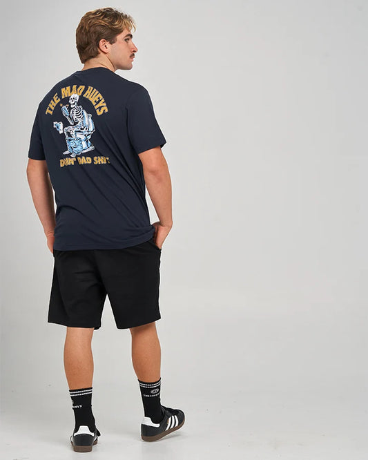 A man wearing a navy blue t-shirt with a large back graphic, black shorts, and black sneakers, photographed from behind against a light gray studio background.