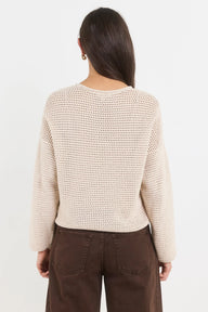 Woman wearing a beige knitted sweater and brown pants on a white background