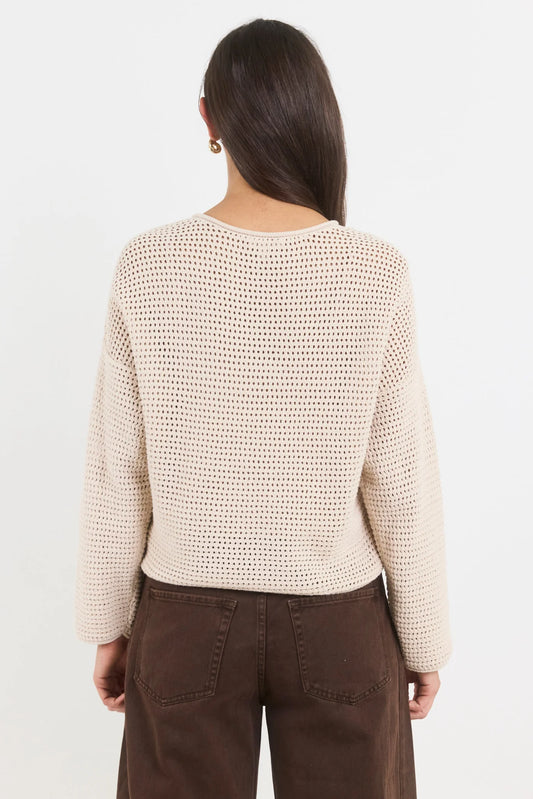 Woman wearing a beige knitted sweater and brown pants on a white background