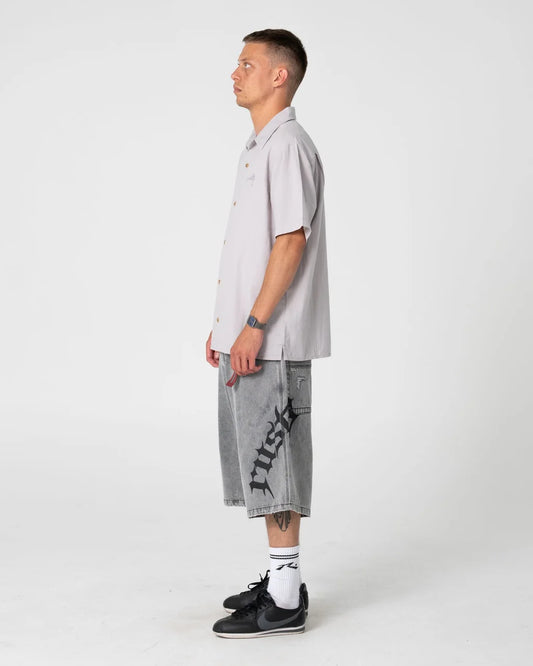 Man wearing a light gray shirt and gray shorts with black text on a white background