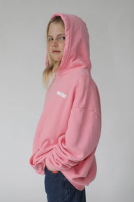 Person wearing a pink hoodie with a logo on a plain background