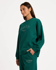 Woman wearing a green sweatshirt with 'ROXY' branding on a white background