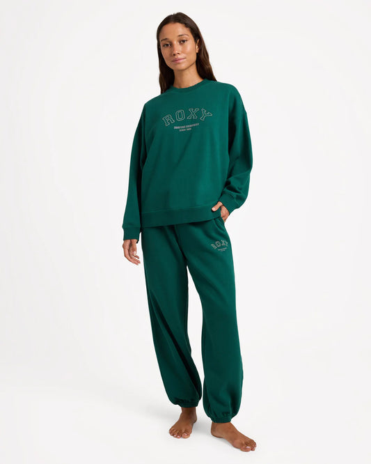 Person wearing a green 'ROXY' sweatshirt and pants on a white background