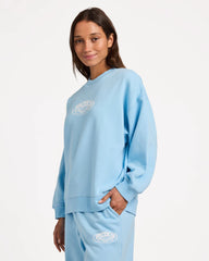 Person wearing a light blue sweatshirt and pants with a logo on a white background