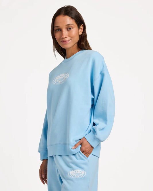 Person wearing a light blue sweatshirt and pants with a logo on a white background