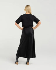 Woman wearing a black outfit with a long skirt on a white background