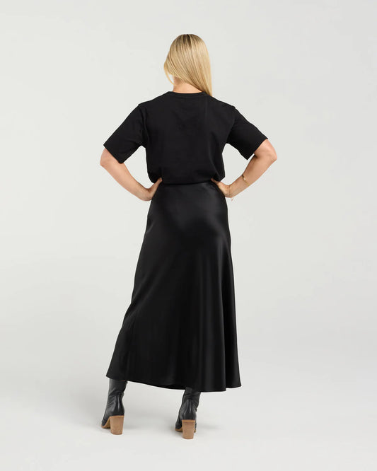 Woman wearing a black outfit with a long skirt on a white background