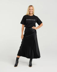Woman wearing a black 'BLACKSTONE' t-shirt and black skirt on a white background