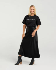 Woman wearing a black 'BLACKSTONE' t-shirt and black skirt on a white background