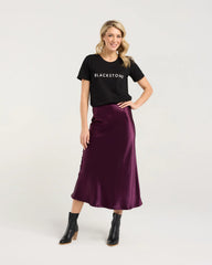 Woman wearing a black t-shirt with 'Blackstone' logo and a purple skirt on a white background