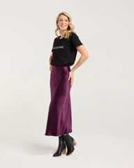 Woman wearing a black t-shirt and purple skirt on a white background