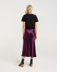 Woman wearing a black t-shirt and purple satin skirt on a white background