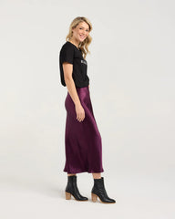 Woman wearing a black t-shirt and purple satin skirt on a white background