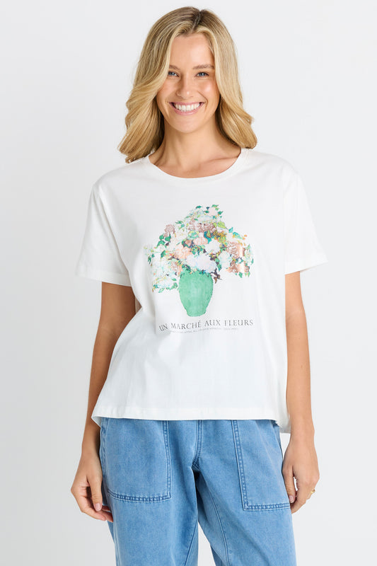Woman wearing a white t-shirt with floral design and text on a plain background